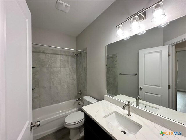 full bathroom with vanity, tiled shower / bath combo, and toilet