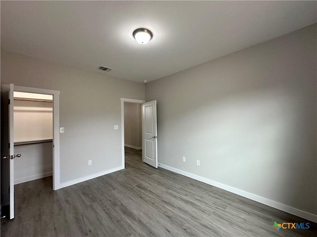 unfurnished bedroom with hardwood / wood-style flooring and a spacious closet