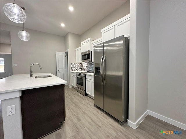 kitchen featuring sink, appliances with stainless steel finishes, white cabinetry, hanging light fixtures, and tasteful backsplash