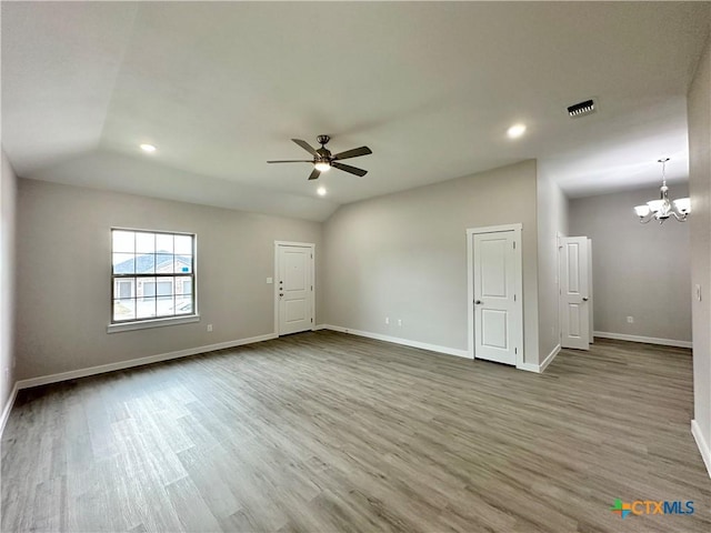 unfurnished room featuring lofted ceiling, hardwood / wood-style floors, and ceiling fan with notable chandelier