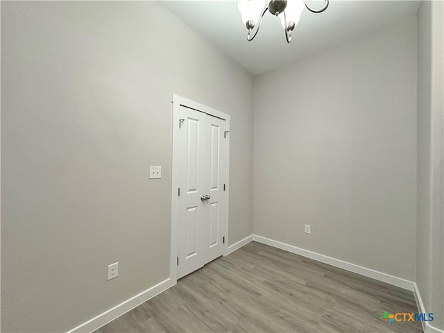 empty room with hardwood / wood-style floors and a notable chandelier