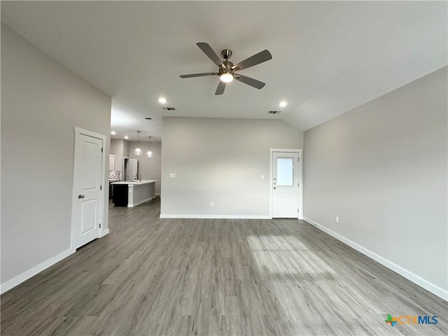 unfurnished living room with dark hardwood / wood-style flooring, vaulted ceiling, and ceiling fan