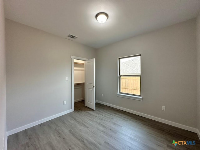 unfurnished bedroom with a walk in closet, wood-type flooring, and a closet