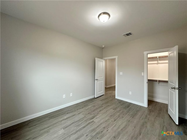 unfurnished bedroom with a walk in closet, light hardwood / wood-style flooring, and a closet