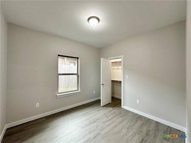 unfurnished bedroom with a walk in closet, light hardwood / wood-style floors, and a closet