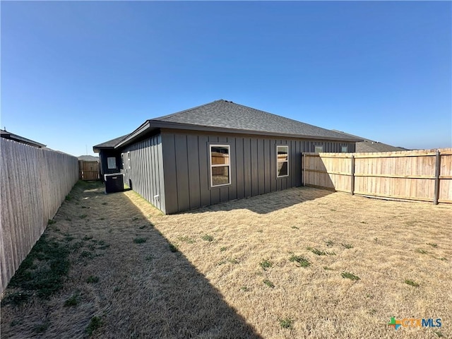 back of house featuring central AC unit and a lawn