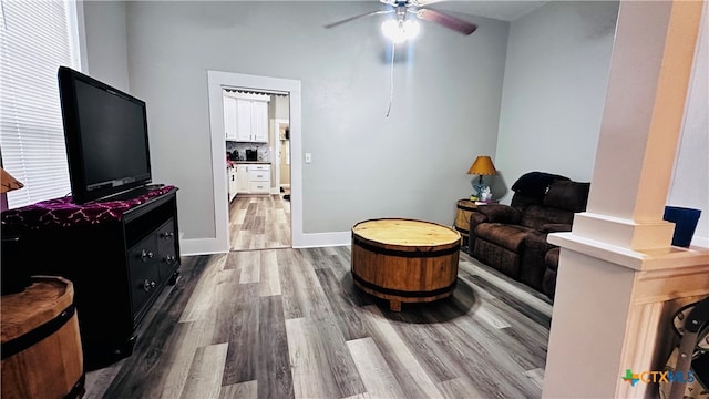 living room with hardwood / wood-style floors, ceiling fan, and ornate columns