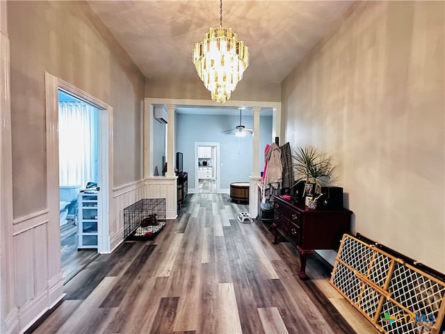 corridor featuring hardwood / wood-style floors, decorative columns, a wall mounted AC, and a notable chandelier