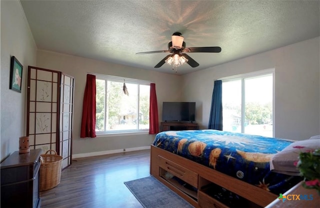 bedroom with hardwood / wood-style floors, ceiling fan, and a textured ceiling