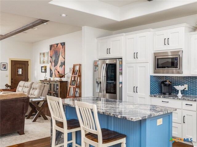 2091 County Road 100, Burnet, TX 78611 - kitchen featuring appliances with stainless steel finishes, a center island, open floor plan, stone countertops, and dark wood-type flooring