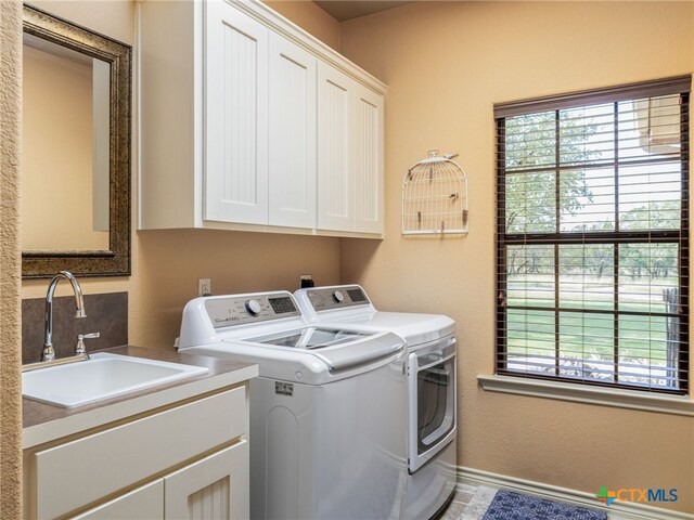 2091 County Road 100, Burnet, TX 78611 - washroom featuring separate washer and dryer, cabinet space, and baseboards