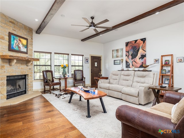 2091 County Road 100, Burnet, TX 78611 - living area with beam ceiling, wood finished floors, ceiling fan, a stone fireplace, and baseboards