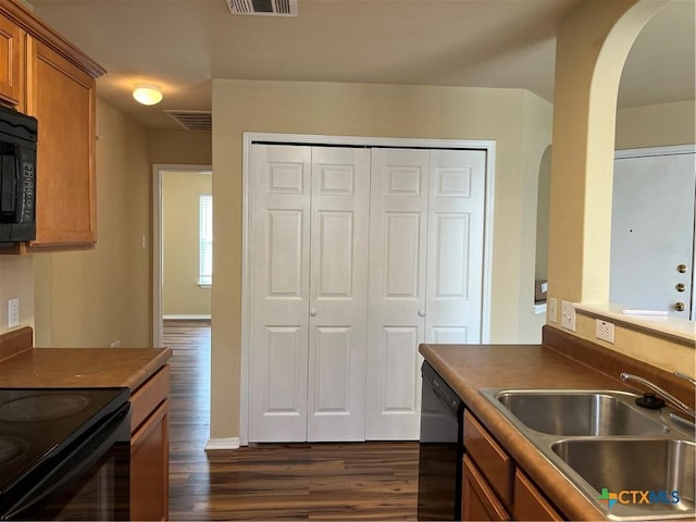 240 Ibis Falls Dr, New Braunfels, TX 78130 - kitchen with arched walkways, a sink, dark wood-type flooring, black appliances, and brown cabinets