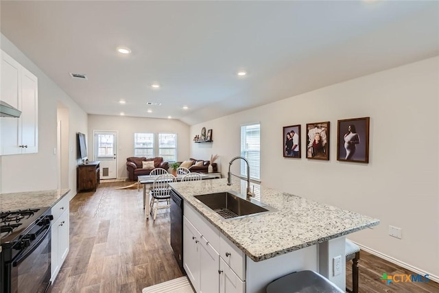 kitchen with white cabinetry, sink, black appliances, and a center island with sink