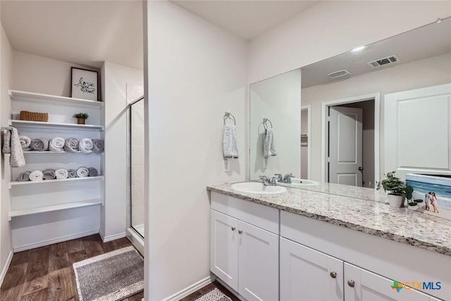 bathroom featuring vanity, wood-type flooring, and a shower with shower door