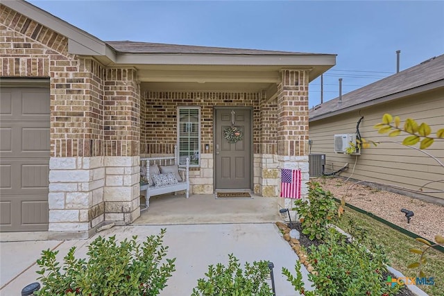 view of exterior entry featuring ac unit, cooling unit, and a garage