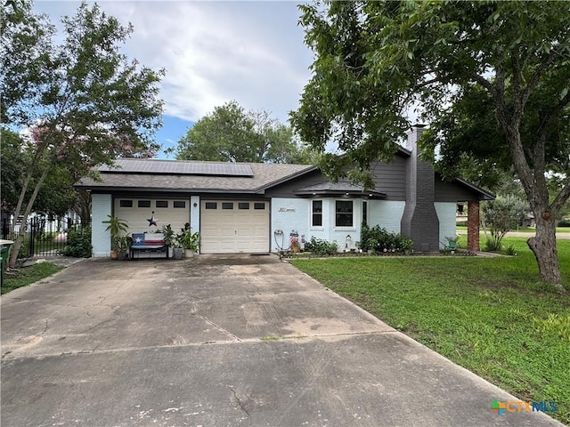 901 Broadmoor St, Victoria, TX 77904 - view of front of home featuring a garage, roof mounted solar panels, a chimney, driveway, and brick siding