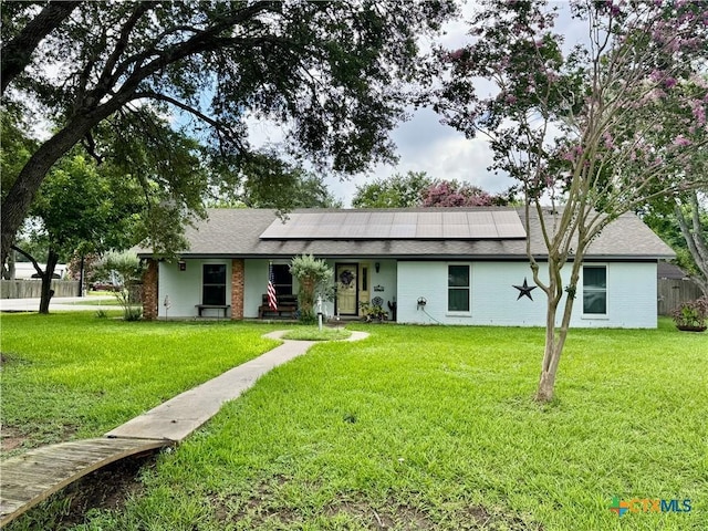 901 Broadmoor St, Victoria, TX 77904 - back of property featuring roof mounted solar panels, a yard, brick siding, and a shingled roof