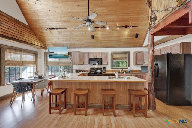 kitchen featuring vaulted ceiling, tile countertops, wooden ceiling, and black appliances