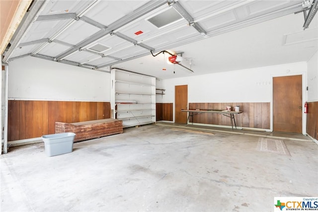 garage featuring a garage door opener and wooden walls