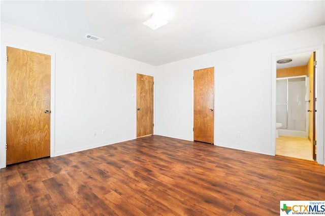 unfurnished bedroom featuring dark hardwood / wood-style floors and ensuite bath