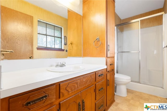 bathroom with a shower with door, vanity, and toilet