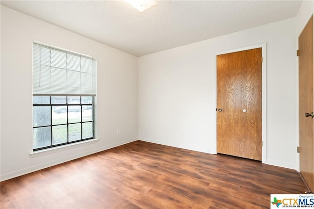 unfurnished room with dark hardwood / wood-style flooring and a textured ceiling