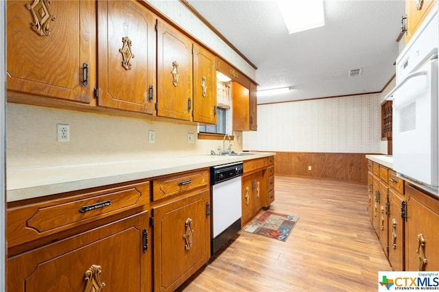 kitchen featuring light wood-type flooring, a textured ceiling, white dishwasher, crown molding, and sink