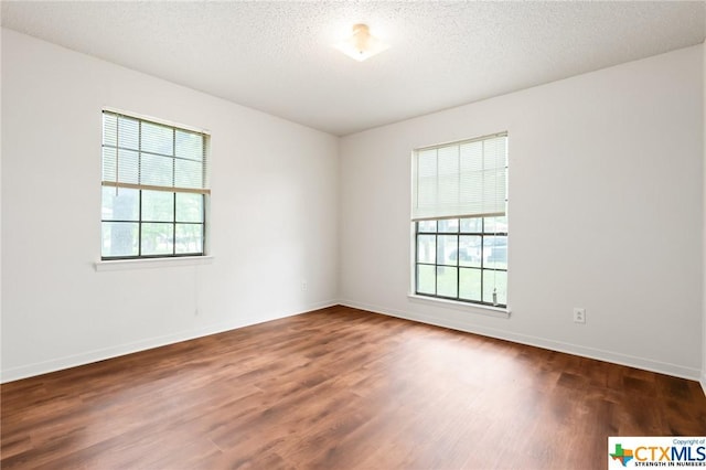 unfurnished room featuring dark wood-type flooring and a textured ceiling