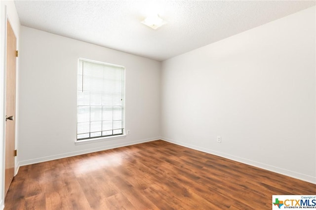 empty room featuring wood-type flooring and a textured ceiling