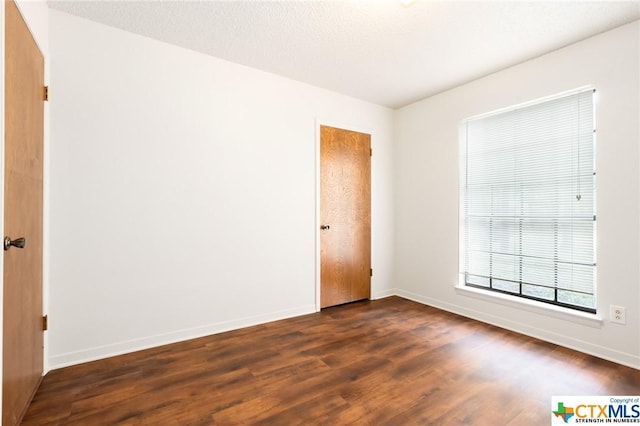 unfurnished room featuring a textured ceiling and dark hardwood / wood-style floors