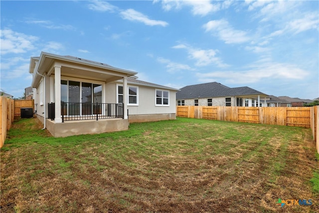 rear view of house with central AC unit and a lawn