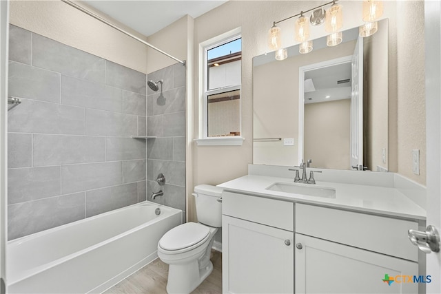 full bathroom with hardwood / wood-style floors, vanity, toilet, and tiled shower / bath