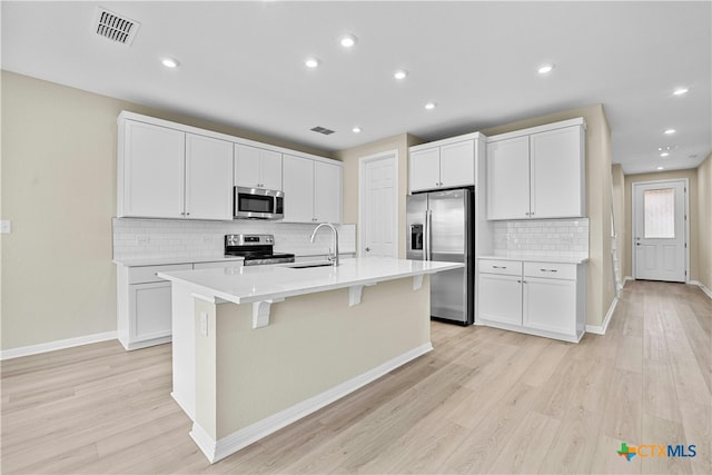 kitchen featuring light hardwood / wood-style floors, sink, stainless steel appliances, and an island with sink