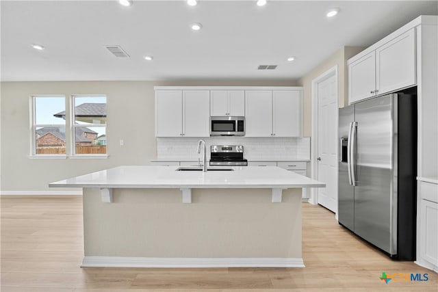 124 Jasmine Ln, Marble Falls, TX 78654 - kitchen with stainless steel appliances, a sink, decorative backsplash, light countertops, and a kitchen island with sink