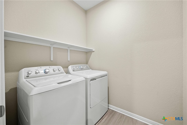 clothes washing area with separate washer and dryer and light hardwood / wood-style flooring