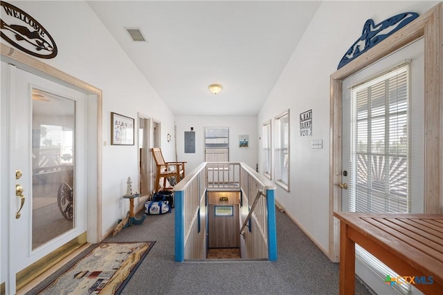 hall with lofted ceiling, electric panel, and dark colored carpet