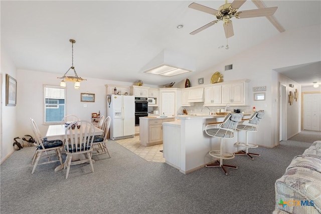 kitchen featuring lofted ceiling, a breakfast bar, decorative light fixtures, a kitchen island, and white appliances