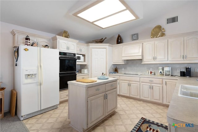 kitchen featuring vaulted ceiling, black appliances, custom range hood, and a center island