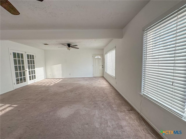 unfurnished living room featuring baseboards, light colored carpet, ceiling fan, a textured ceiling, and french doors