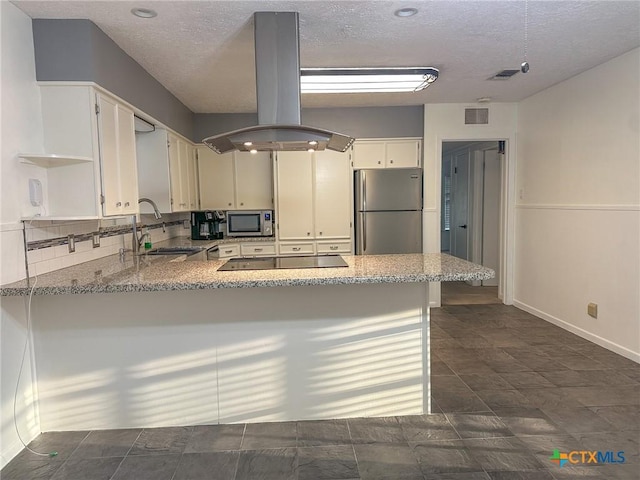 kitchen with a peninsula, light stone countertops, island exhaust hood, and stainless steel appliances