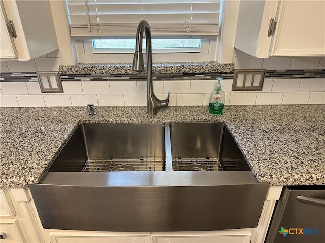 interior details with stone counters, a sink, white cabinets, and decorative backsplash