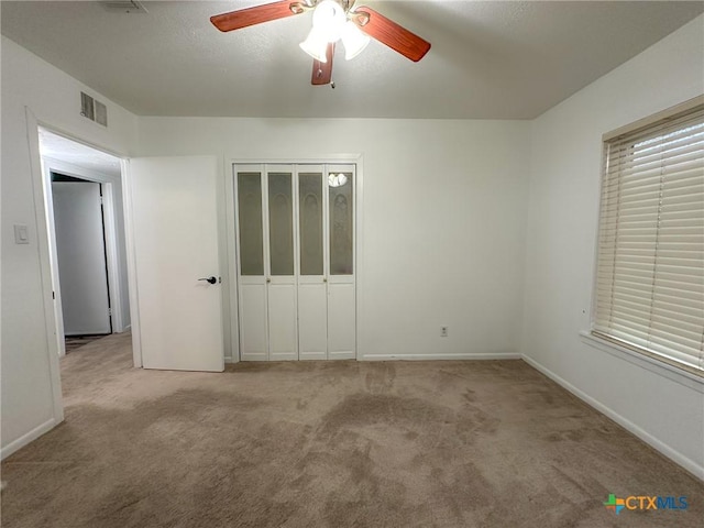 unfurnished bedroom with a closet, light colored carpet, visible vents, ceiling fan, and baseboards