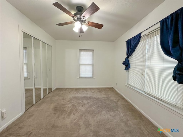 unfurnished bedroom with light carpet, ceiling fan, baseboards, and a closet