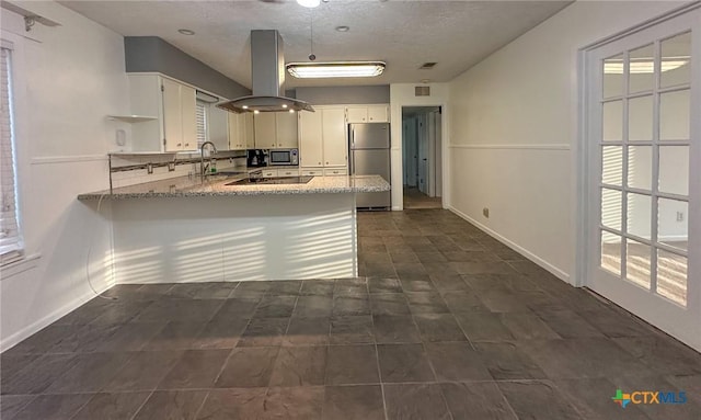 kitchen with a peninsula, stainless steel appliances, white cabinetry, and island range hood