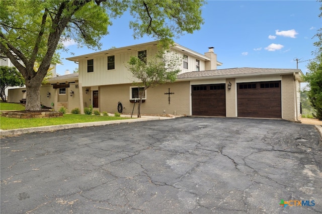 95 Mission Dr, New Braunfels, TX 78130 - view of front facade with aphalt driveway, an attached garage, brick siding, a chimney, and board and batten siding
