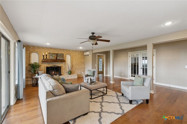 95 Mission Dr, New Braunfels, TX 78130 - living room with a wall mounted air conditioner, french doors, wood finished floors, a brick fireplace, and a ceiling fan