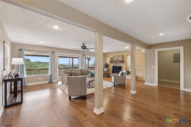 95 Mission Dr, New Braunfels, TX 78130 - living area featuring baseboards, a ceiling fan, a fireplace, and hardwood / wood-style flooring