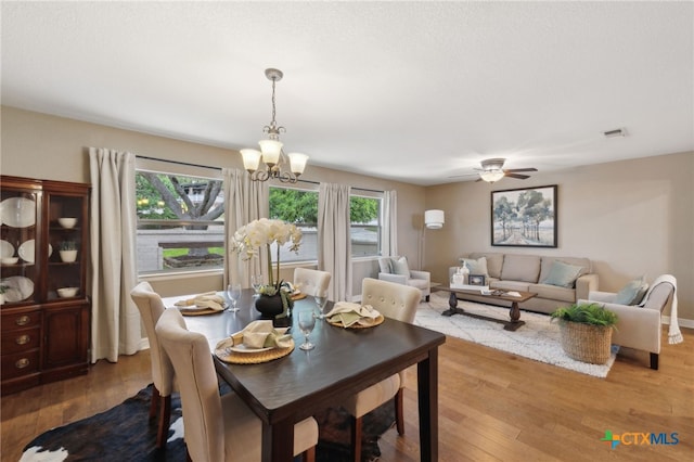 95 Mission Dr, New Braunfels, TX 78130 - dining room with visible vents, wood finished floors, and ceiling fan with notable chandelier