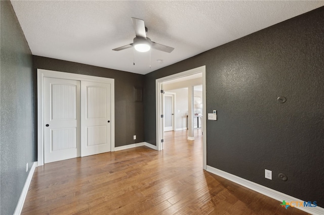 95 Mission Dr, New Braunfels, TX 78130 - unfurnished bedroom with baseboards, a closet, wood finished floors, and a textured wall